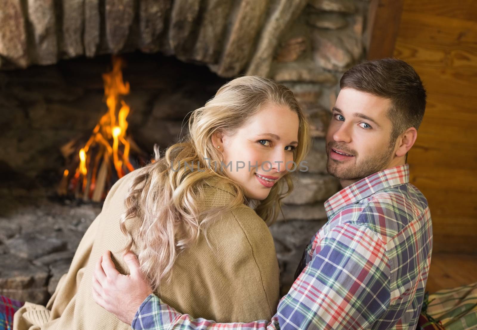 Romantic young couple in front of lit fireplace by Wavebreakmedia