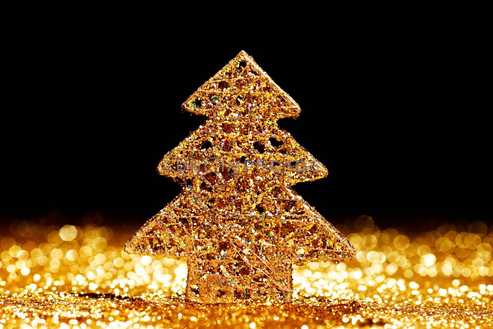 Beautiful golden decorative christmas tree on golden glitter background with black copy space