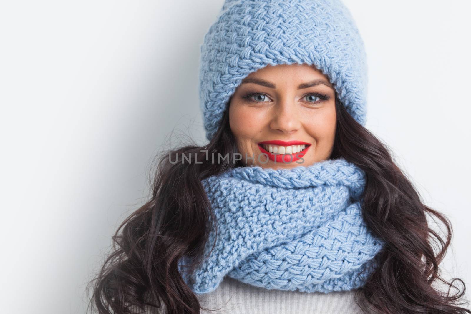Beautiful woman in blue warm hat and scarf on white background