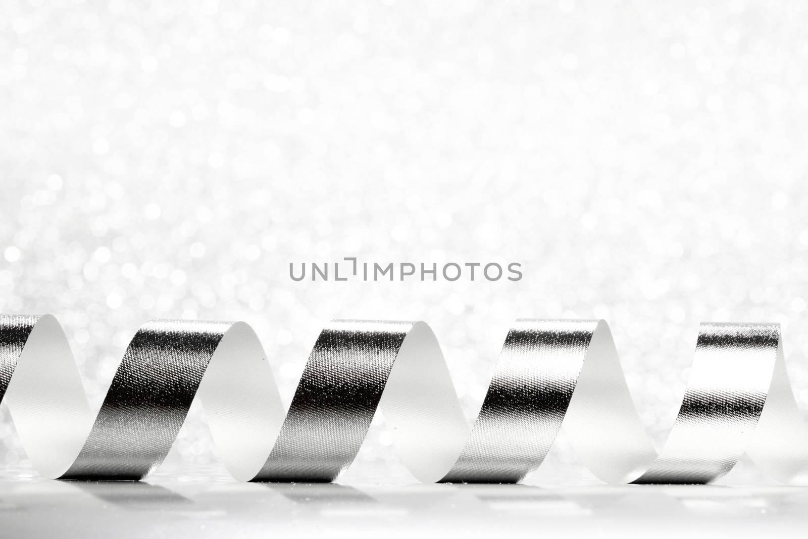 Curly silver serpentine on shiny glitter background, holiday concept