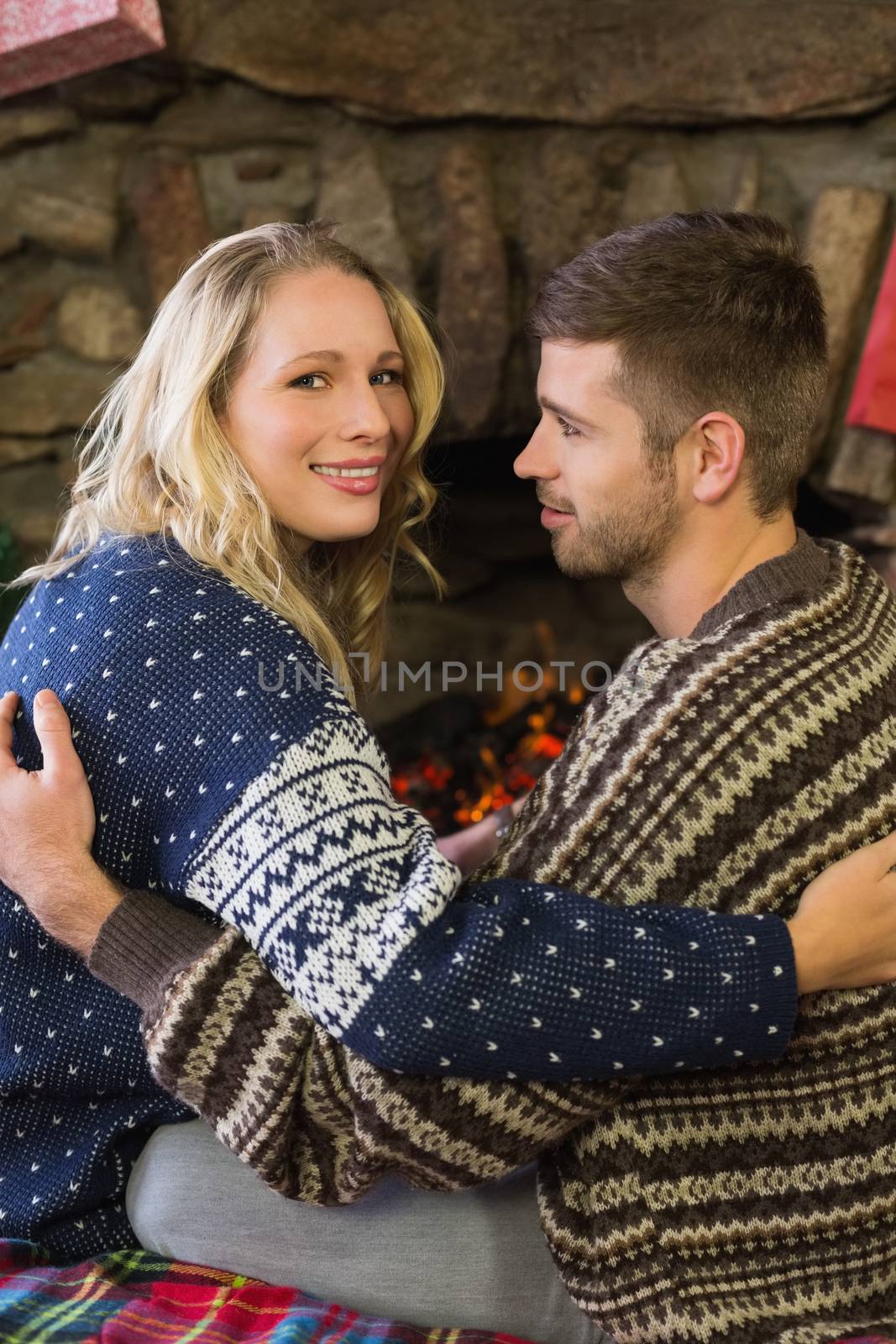 Side view portrait of a romantic young couple smiling in front of fireplace