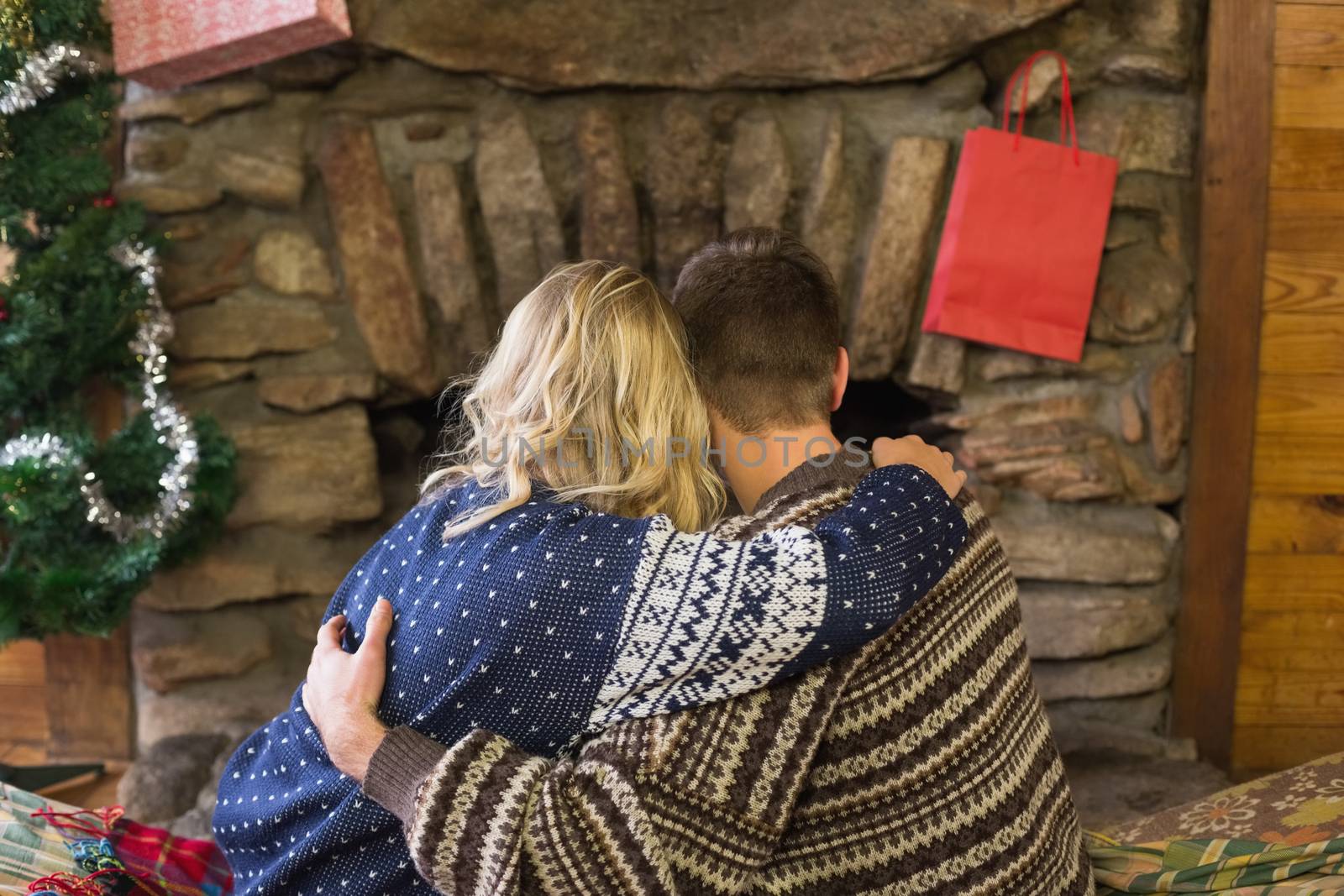 Rear view of a romantic young couple embracing in front of fireplace