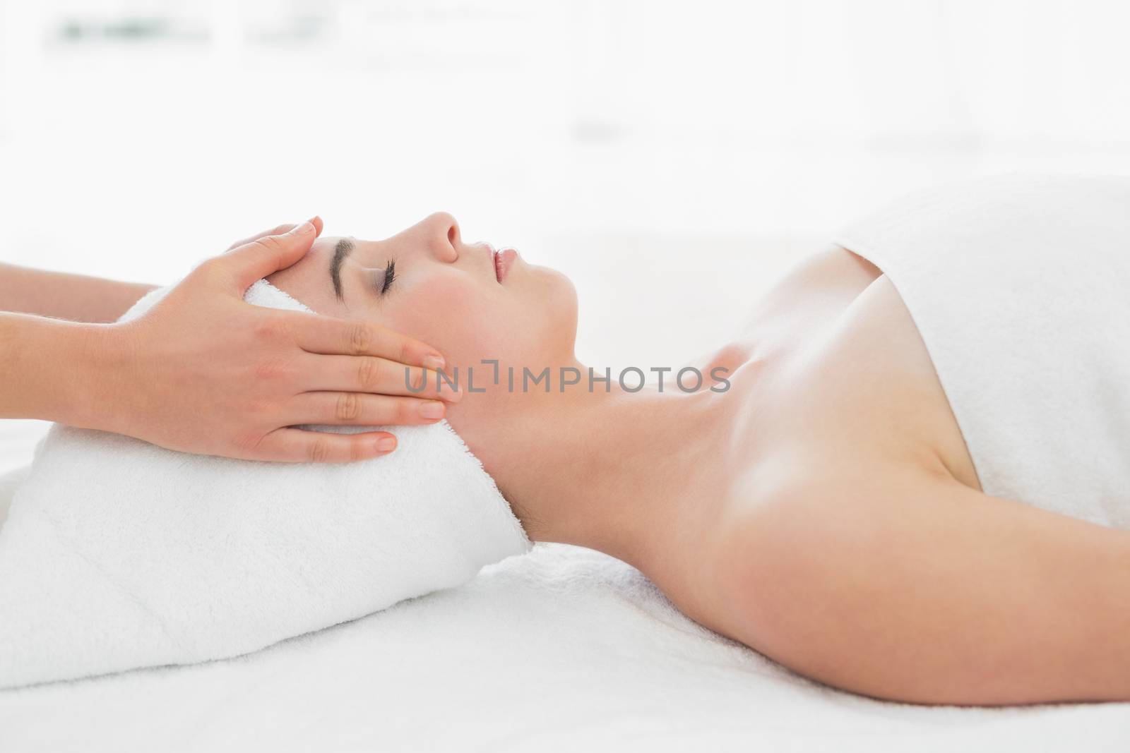 Side view of hands massaging a beautiful womans face at beauty spa