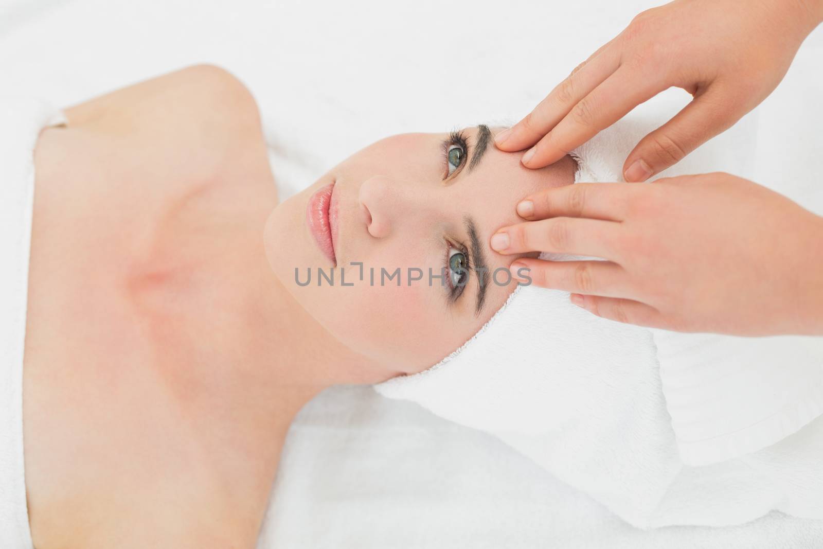 Close up of hands massaging a beautiful womans forehead at beauty spa