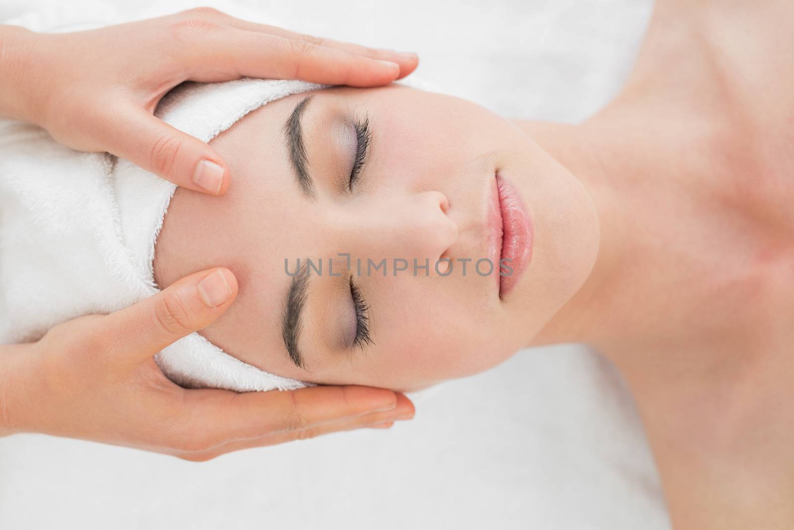 Close up of hands massaging a beautiful womans forehead at beauty spa