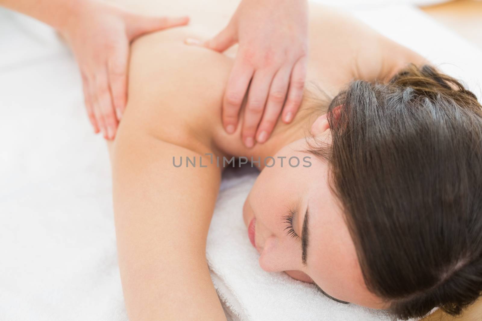 Close up of a beautiful woman enjoying shoulder massage at beauty spa