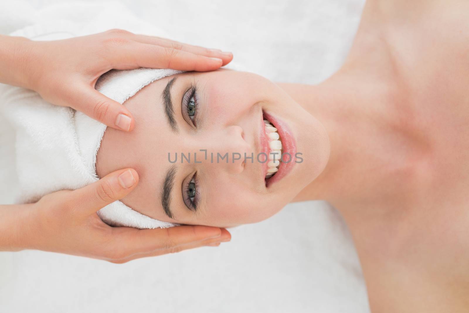 Close up of hands massaging a beautiful womans forehead at beauty spa