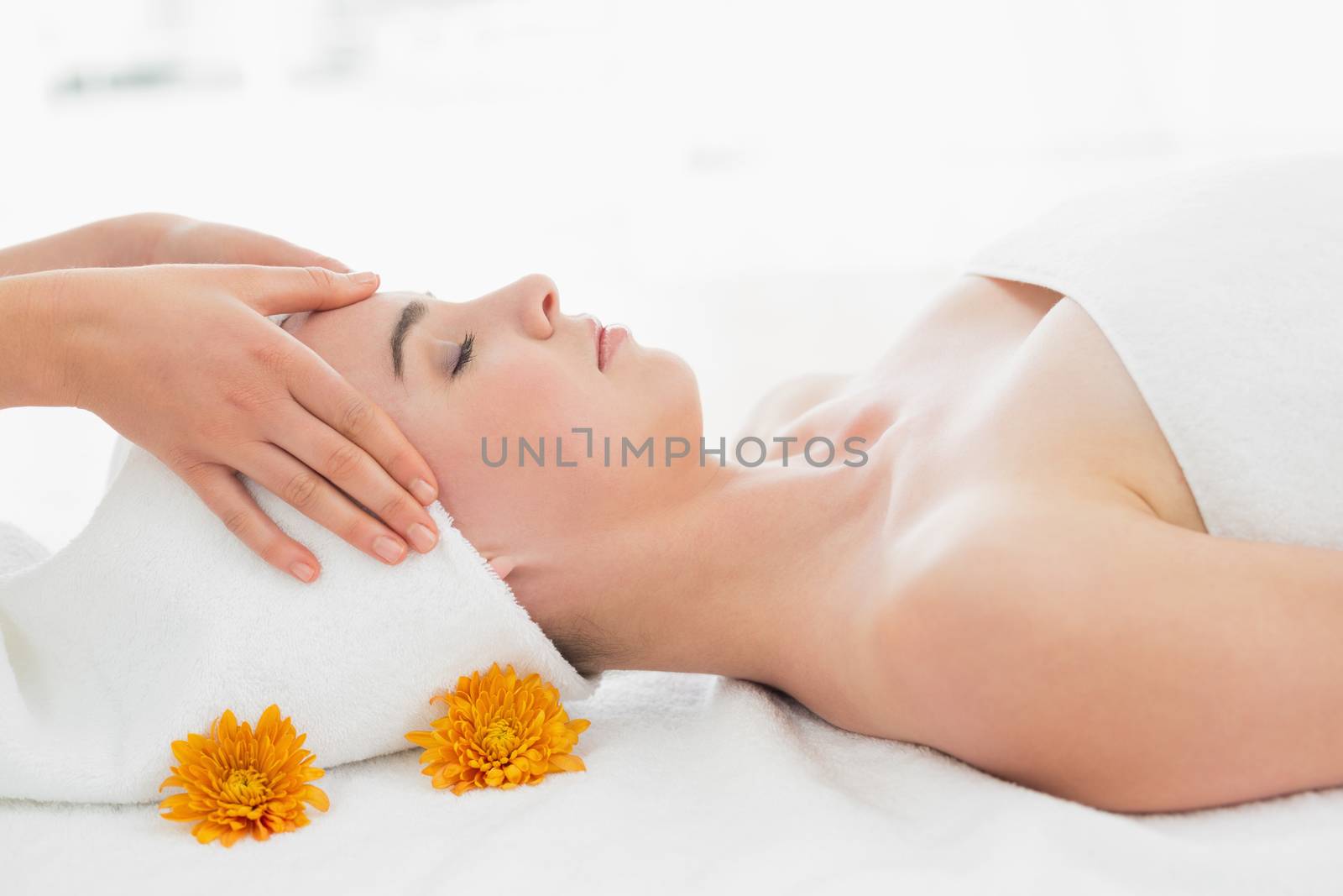 Side view of hands massaging a beautiful womans face at beauty spa