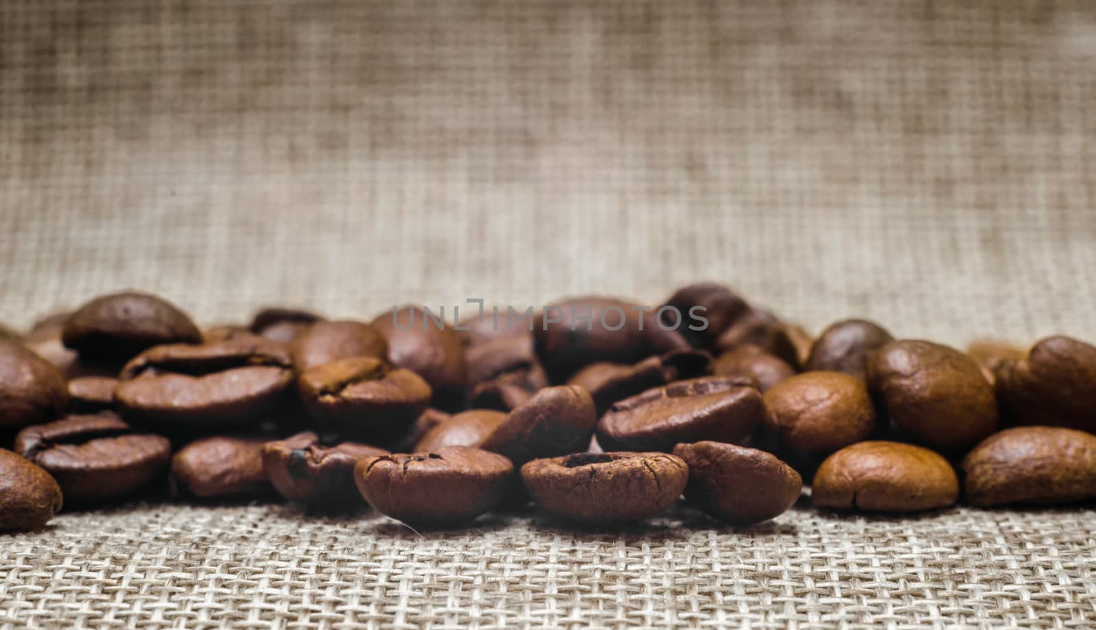 many coffee beans on a matting macro beige background close up