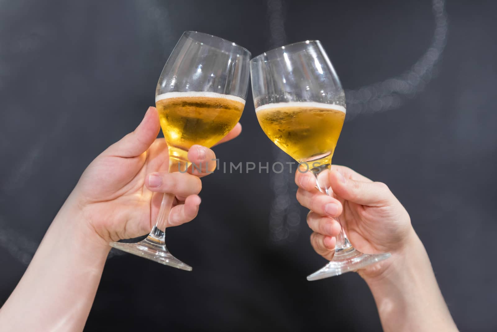 Two friends toasting with glasses of beer at the pub. Blackboard background. by HERRAEZ