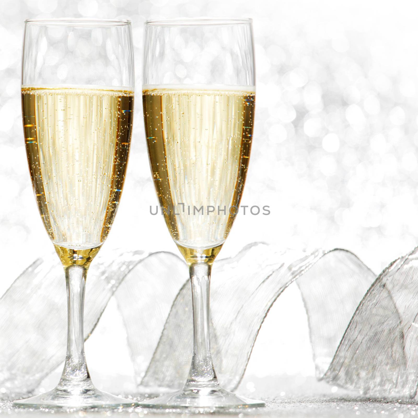 Two glasses of champagne with bow on silver background