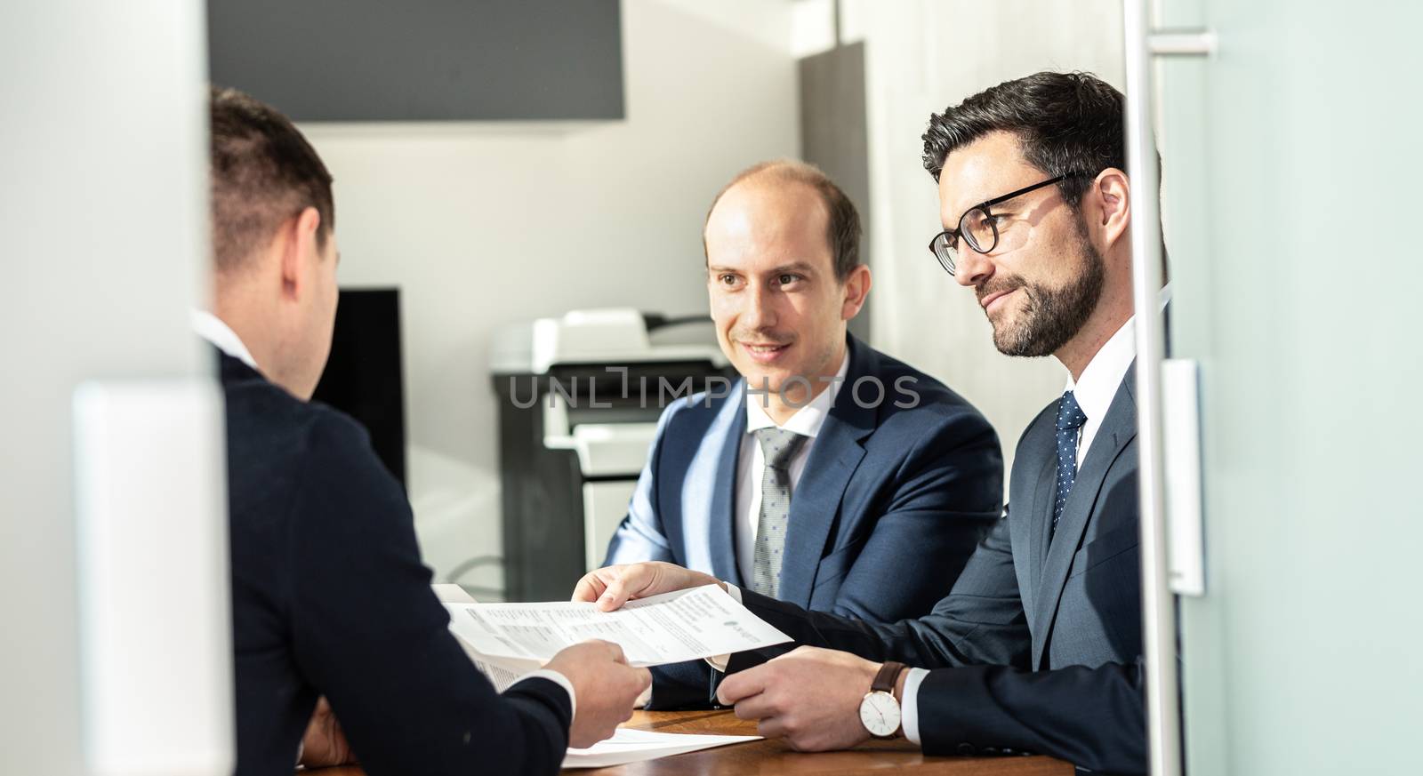 Group of confident successful business people reviewing and signing a contract to seal the deal at business meeting in modern corporate office. by kasto