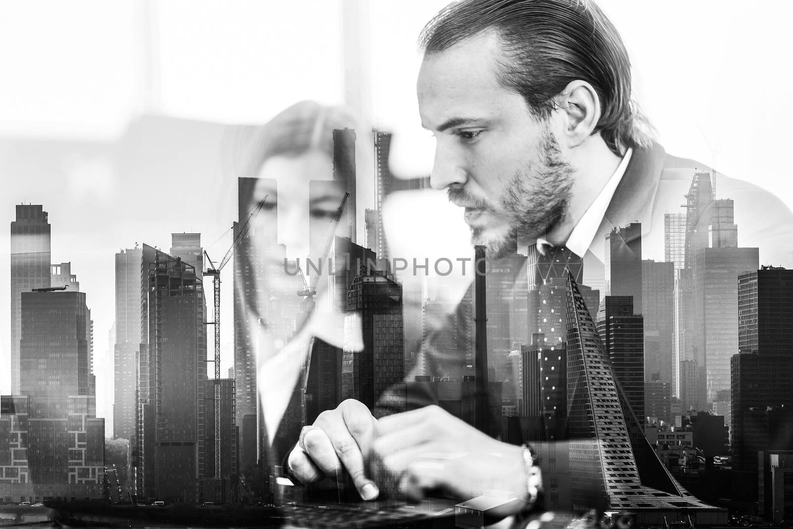 Business people working on laptops in modern office against new york city manhattan buildings and skyscrapers window reflections. Real estate investment and agency concept.