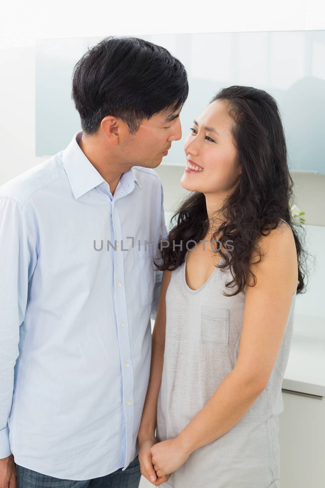 Side view of a romantic young couple in kitchen by Wavebreakmedia