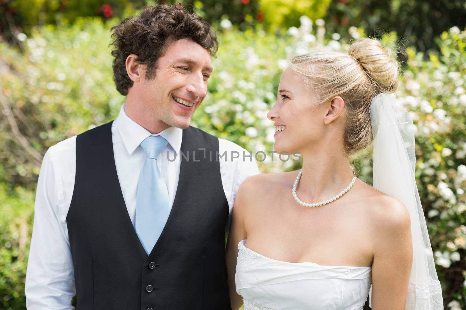 Romantic happy newlywed couple smiling at each other in the countryside