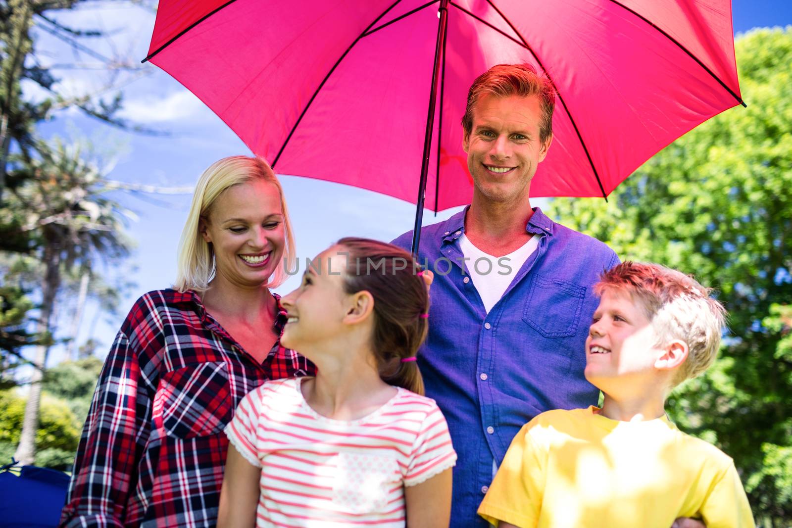 Family standing under umbrella by Wavebreakmedia