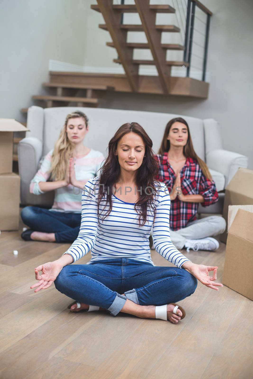 Friends performing yoga in their new house by Wavebreakmedia