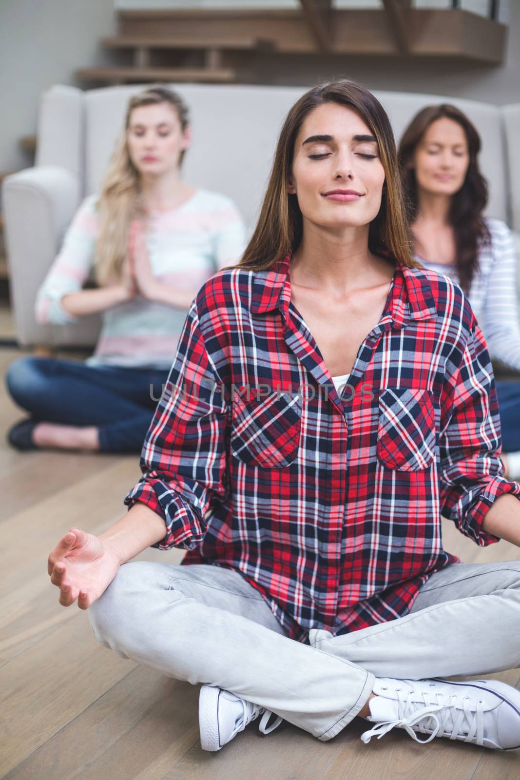 Three friends performing yoga in their new house