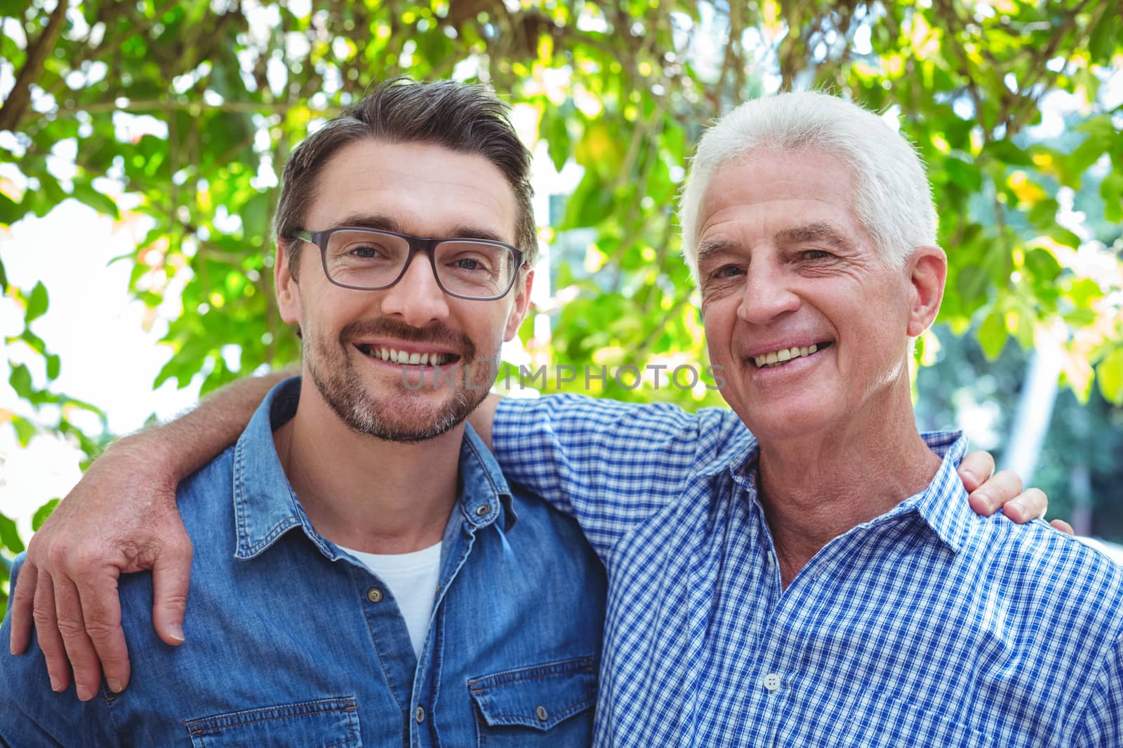 Portrait of happy father and son with arm around while standing outdoors