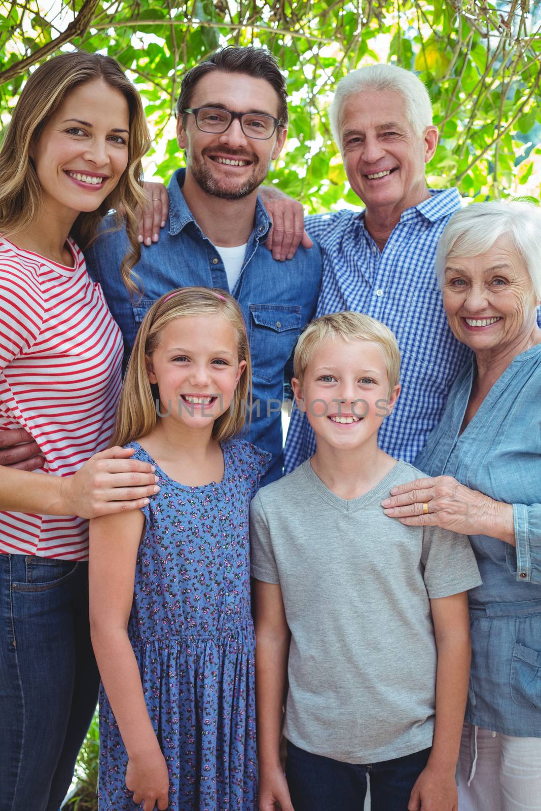 Portrait of smiling multi generation family standing against tree