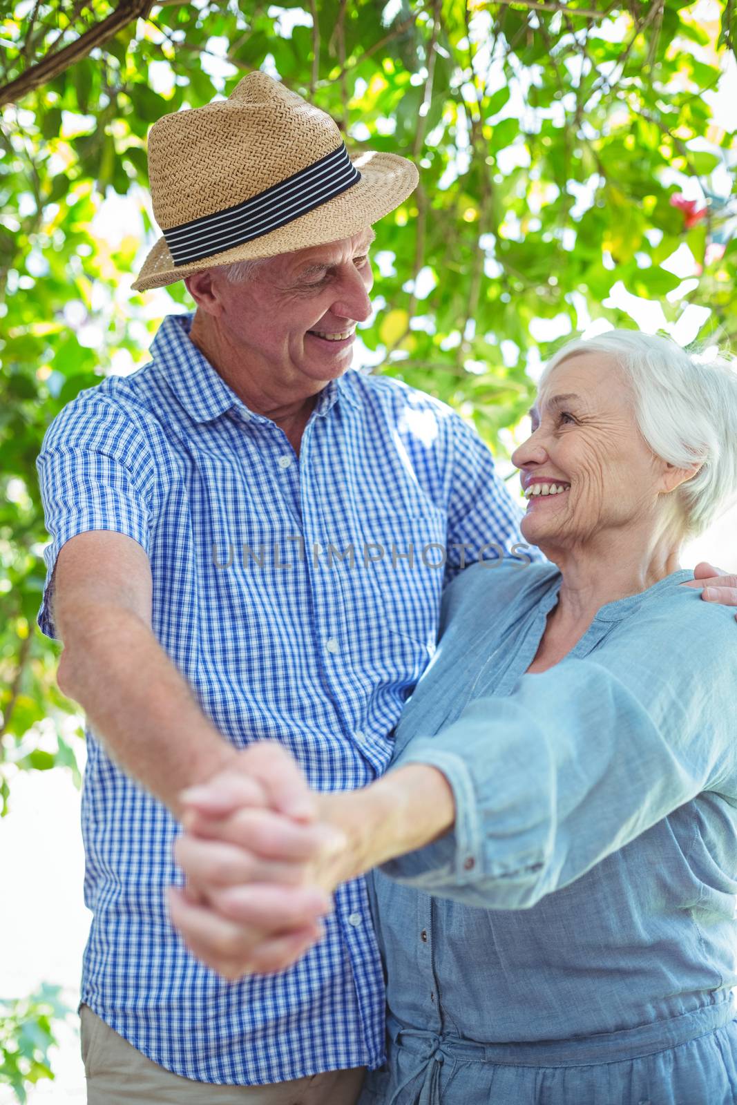 Happy retired couple dancing while standing outdoors