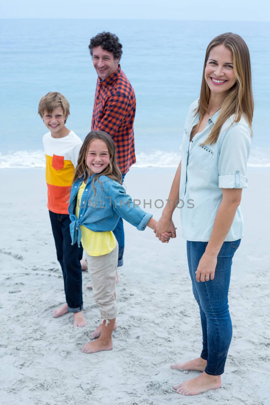 Portrait of happy family standing at sea shore by Wavebreakmedia