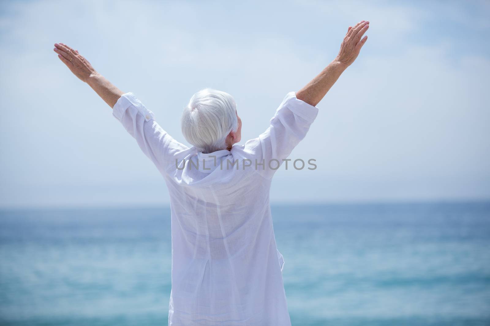 Rear view of senior woman exercising at beach on sunny day