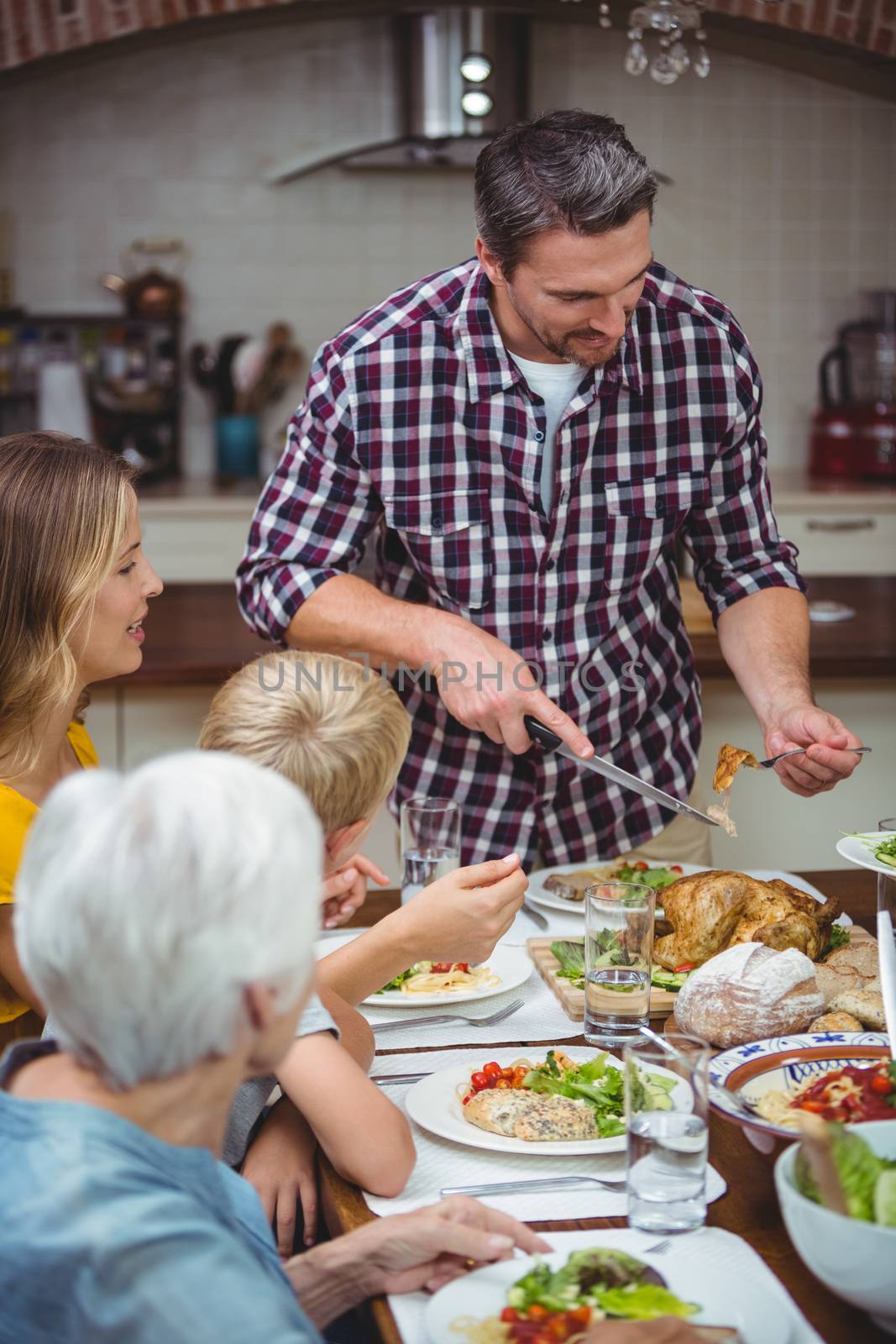 Father serving food while standing at dining table  by Wavebreakmedia