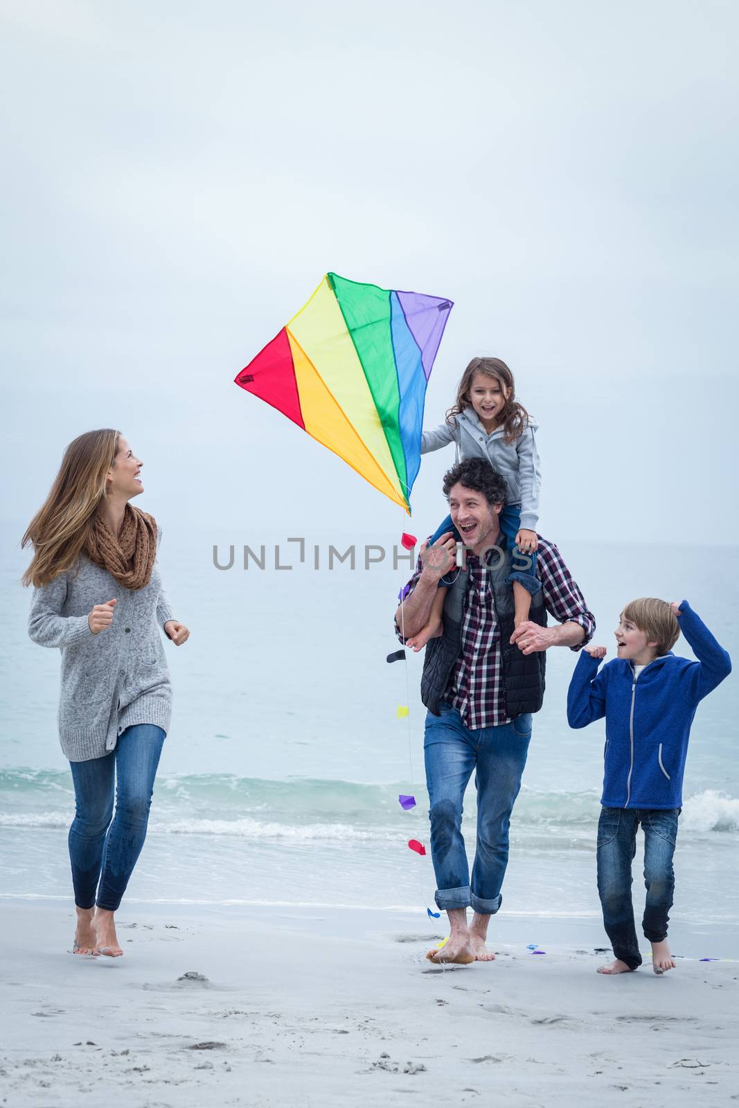 Full length of happy family with kite enjoying at sea shore