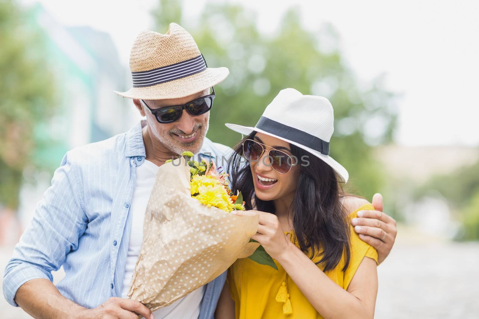 Happy couple with bouquet standing outdoors