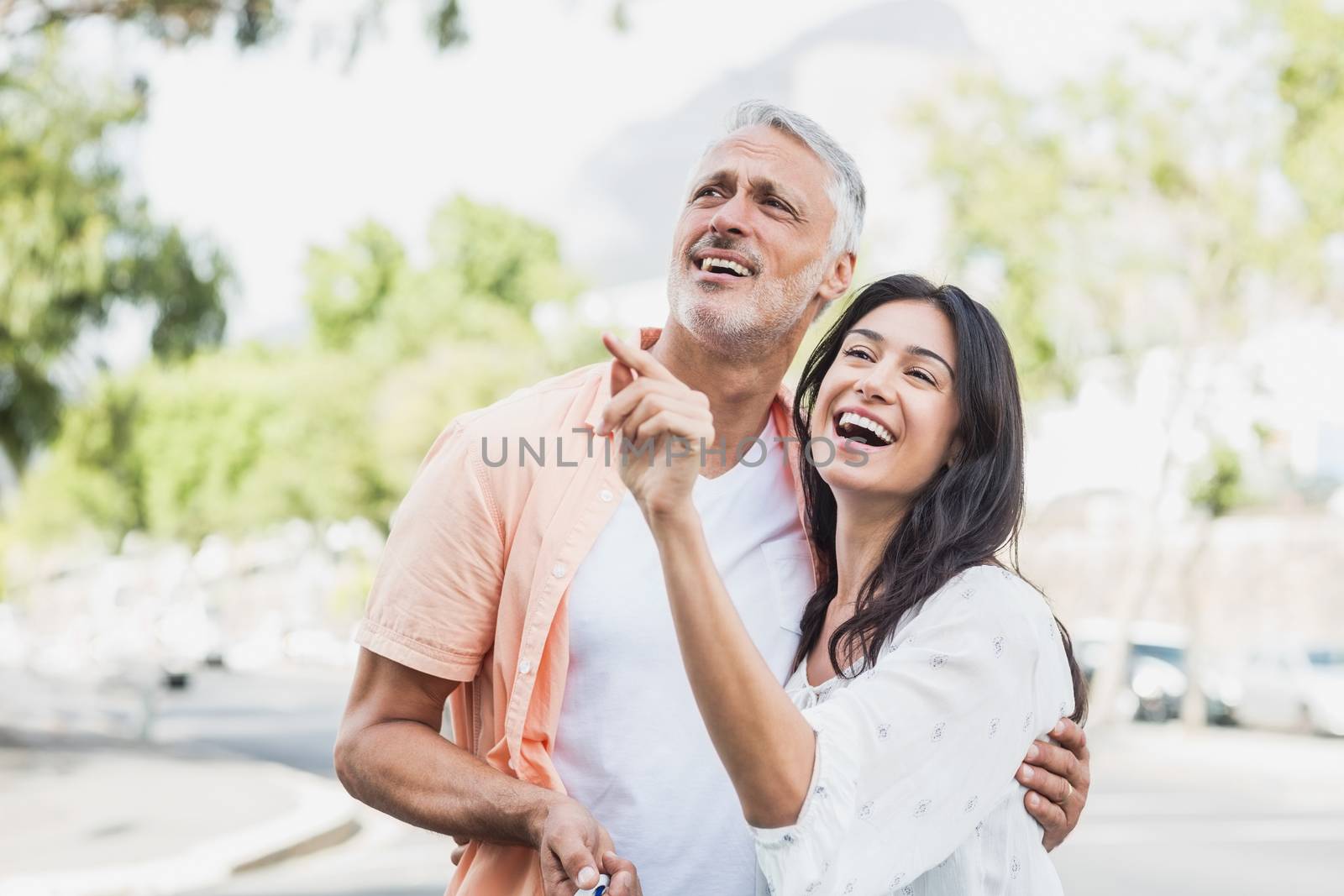 Woman pointing to happy man standing outdoors