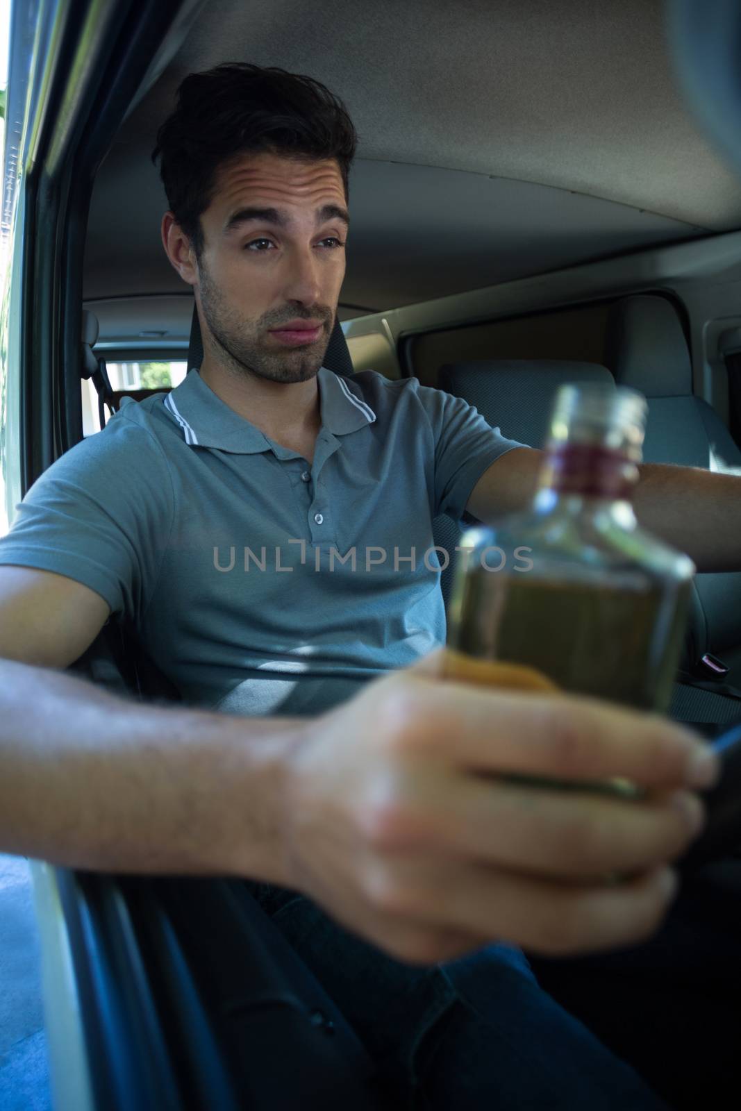 Slumped man with alcohol bottle while driving car