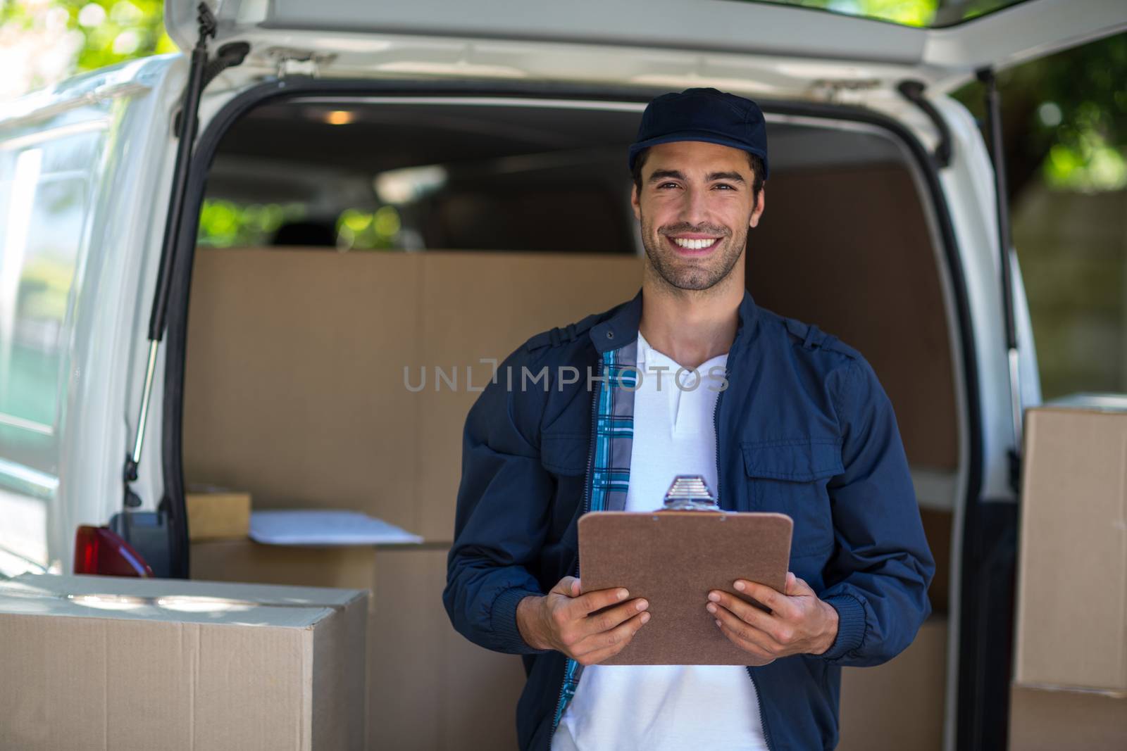 Portrait of smart delivery man holding clipboard  by Wavebreakmedia