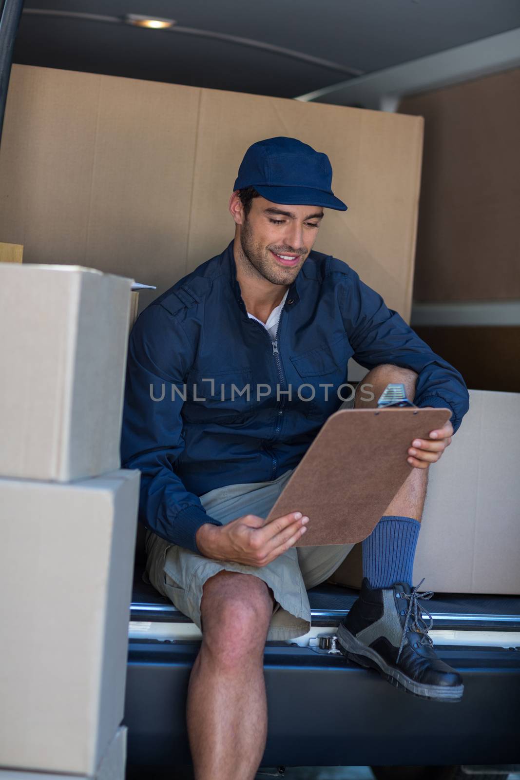 Smiling delivery person with clipboard by Wavebreakmedia