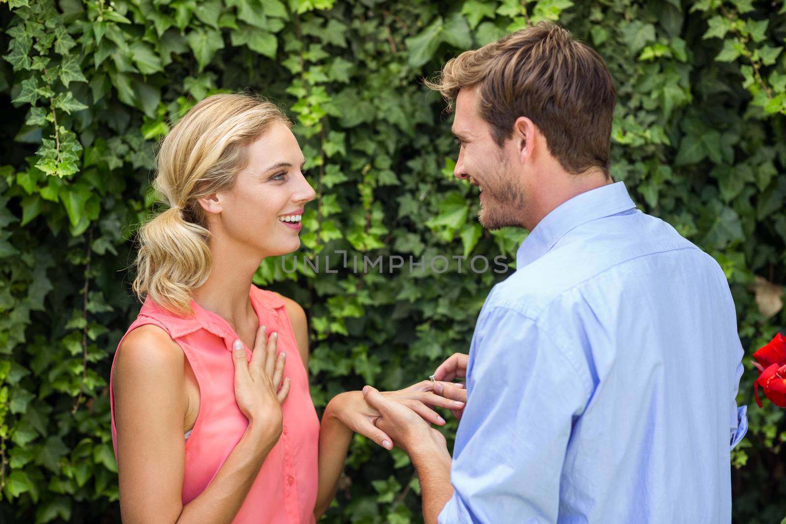 Happy romantic man wearing ring to woman at front yard