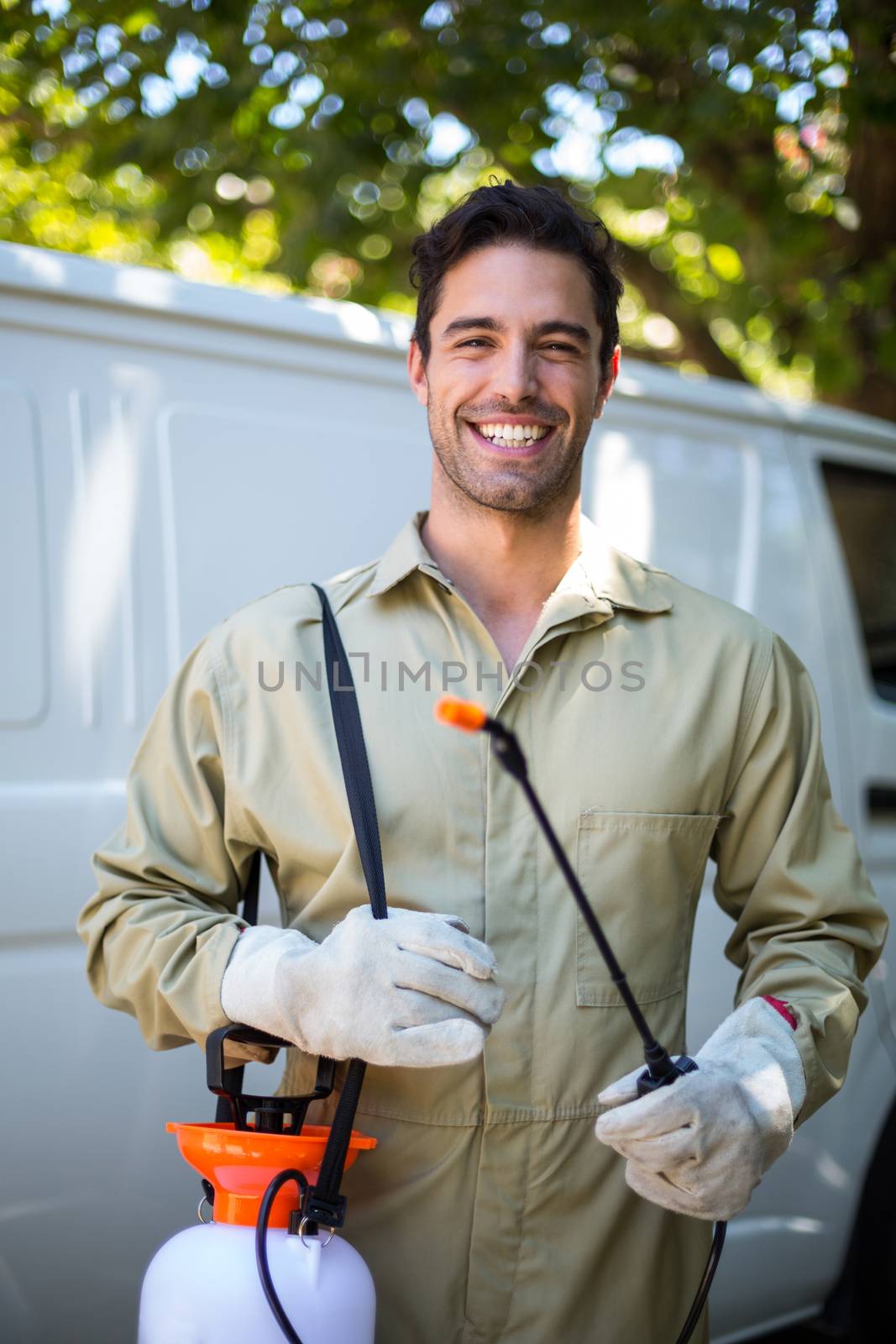 Portrait of happy worker with pesticide sprayer while standing by van