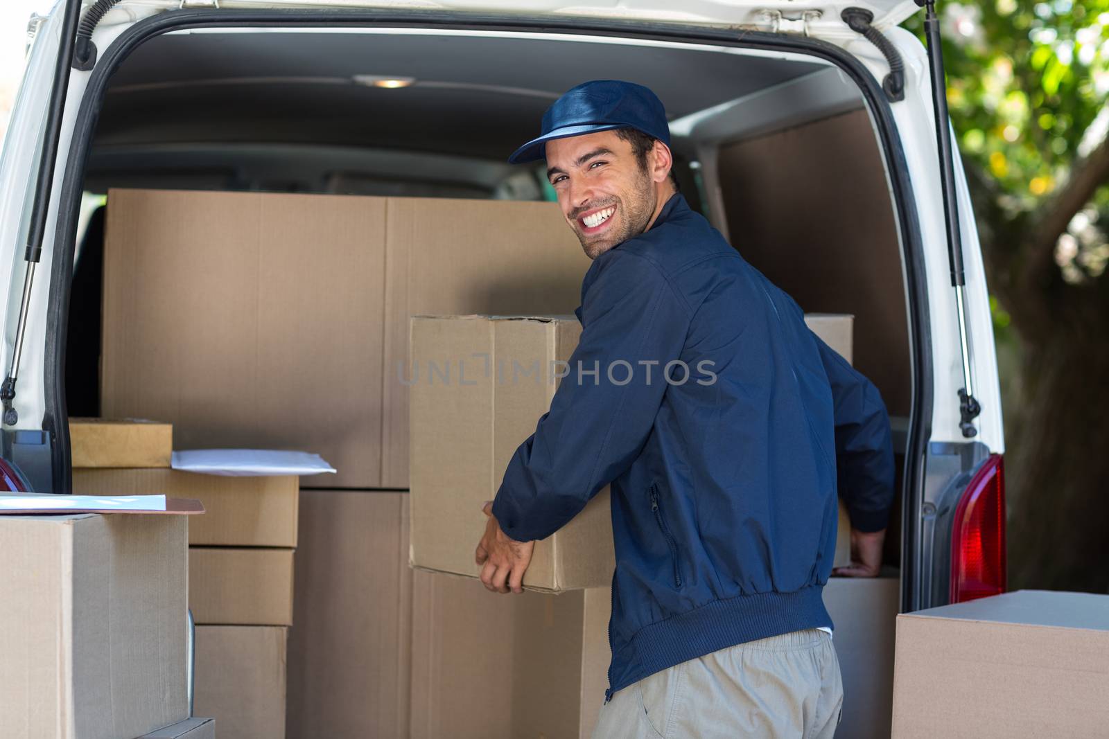 Happy delivery man loading cardboard box in van by Wavebreakmedia