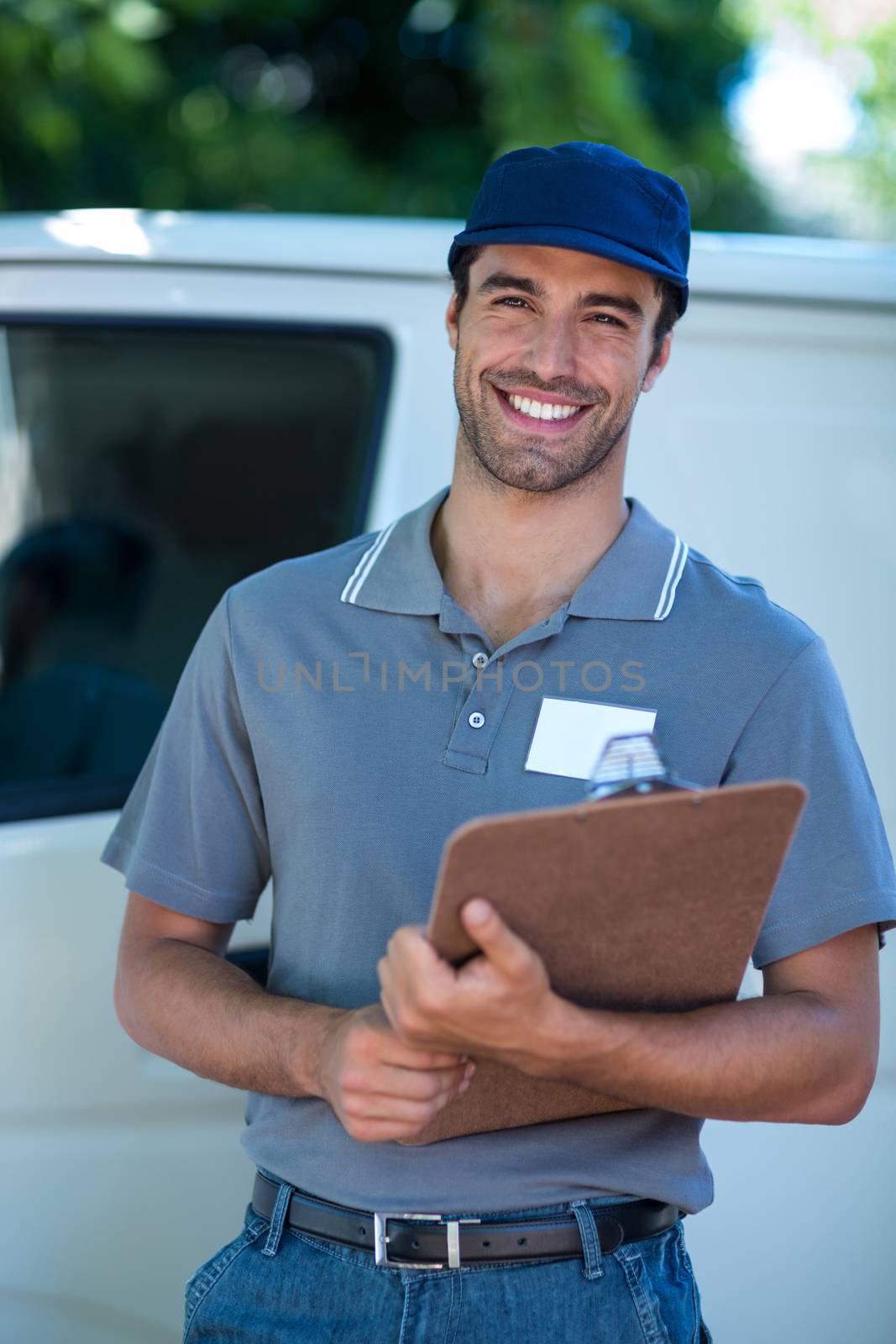 Smiling delivery person holding clipboard by Wavebreakmedia