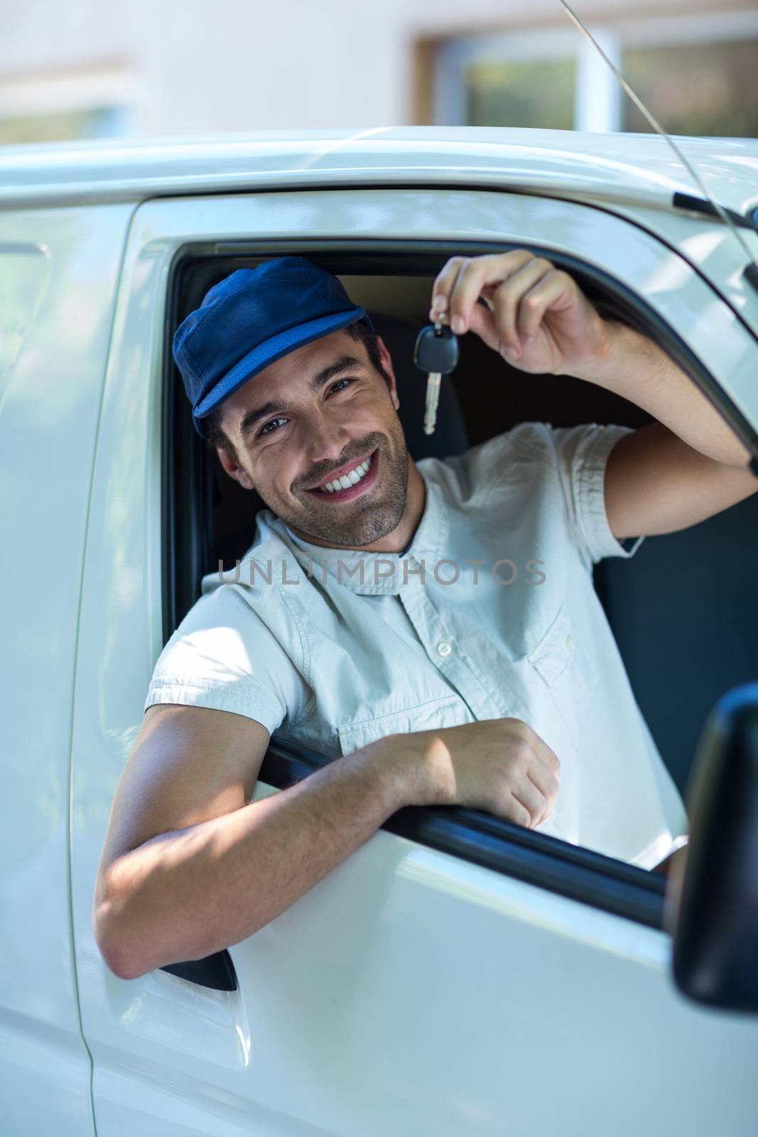 Portrait of smiling delivery man showing car keys while sitting in van