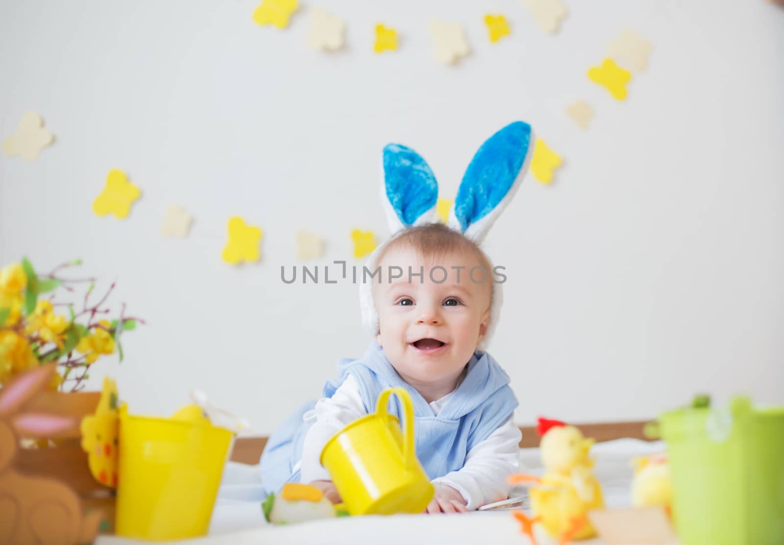 Baby boy with Easter bunny ears and colorful eggs and flowers