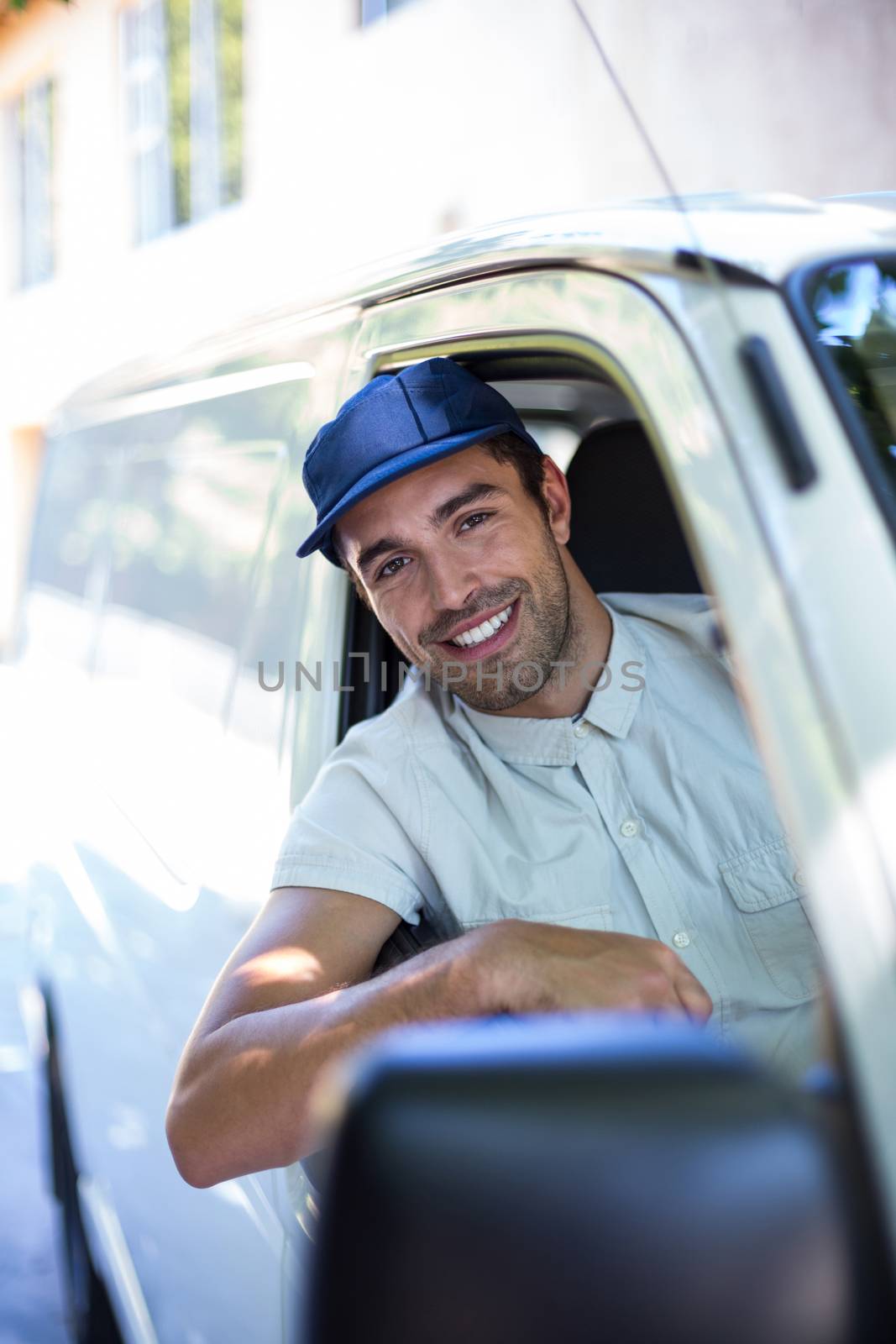 Smiling delivery person sitting in van by Wavebreakmedia