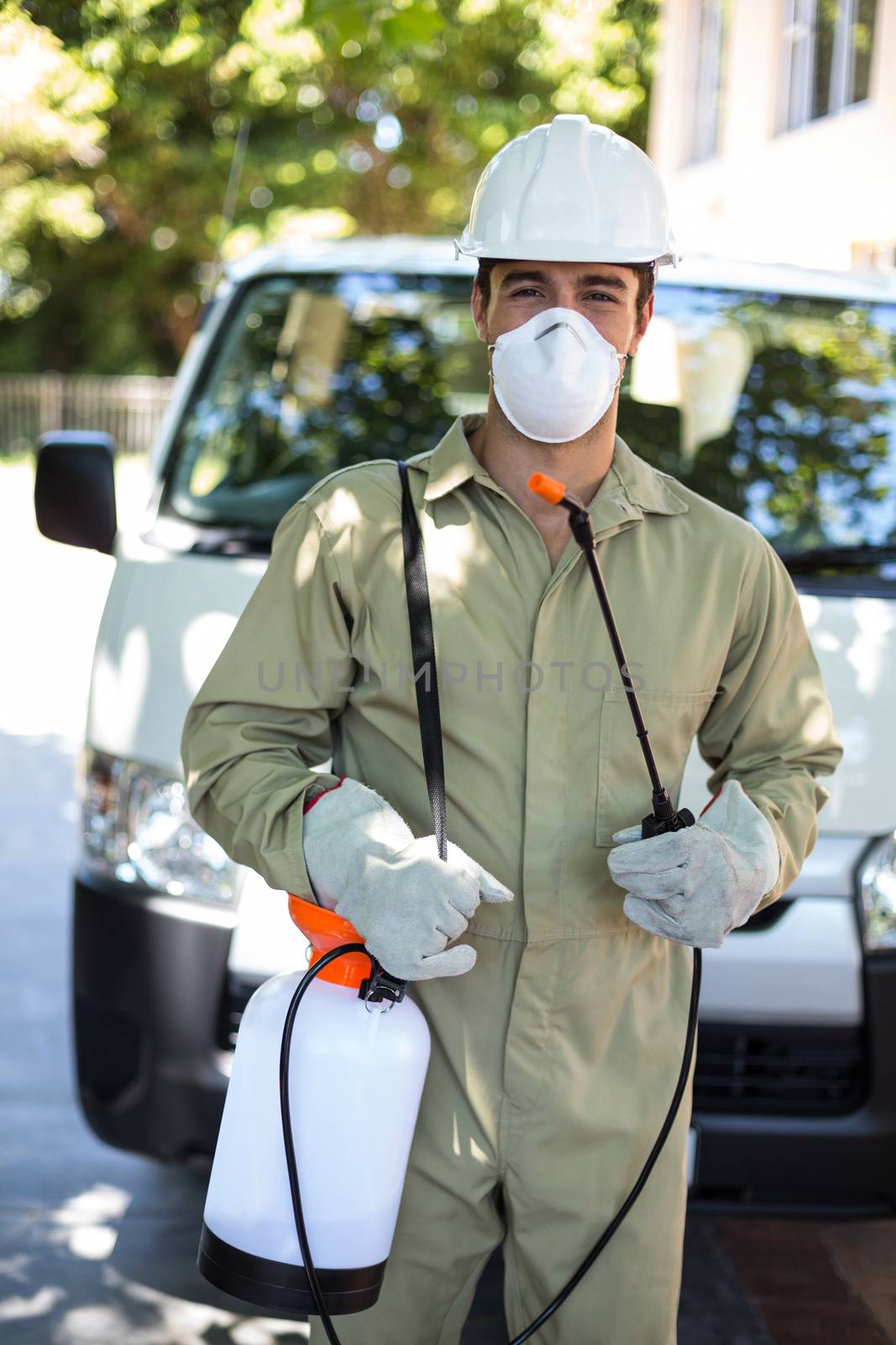 Portrait of worker with pesticide sprayer while standing by van