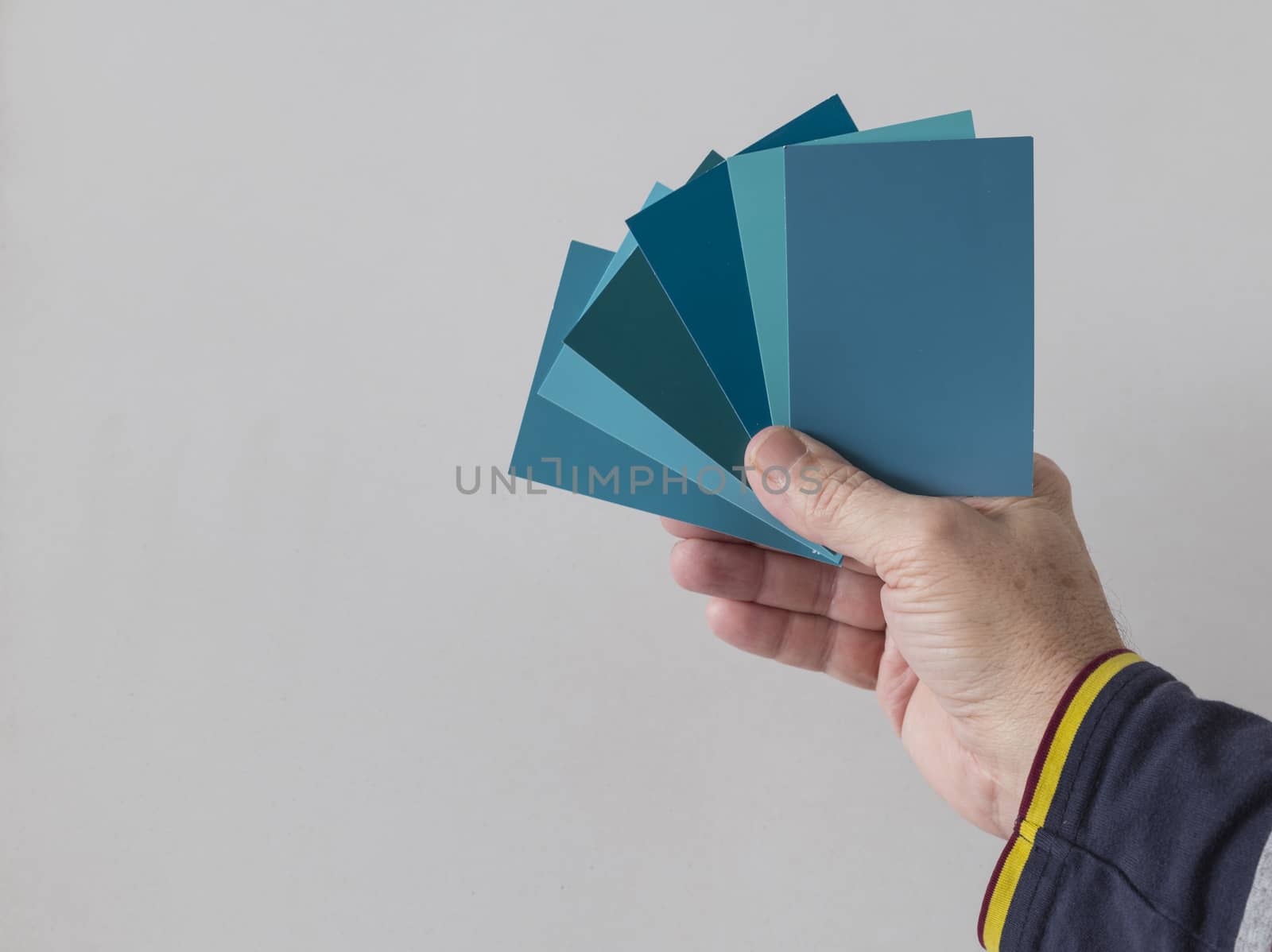 hand of a man with different color swatches for determining the right color of paint on a wall
