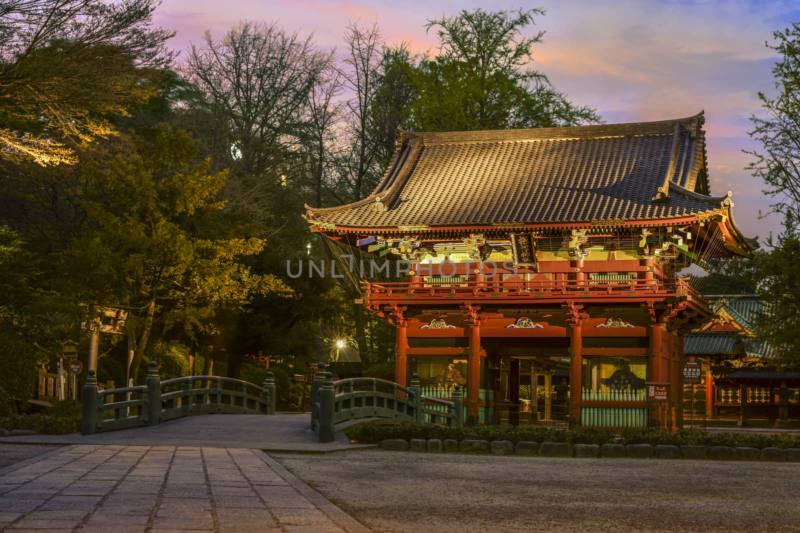 Bridge named bridge of the gods "神橋"　(shinbashi) and central gate named the cherry door "桜門" (sakuramon) of the Shintoist Nezu shrine of the 18th century in Tokyo at sunset.