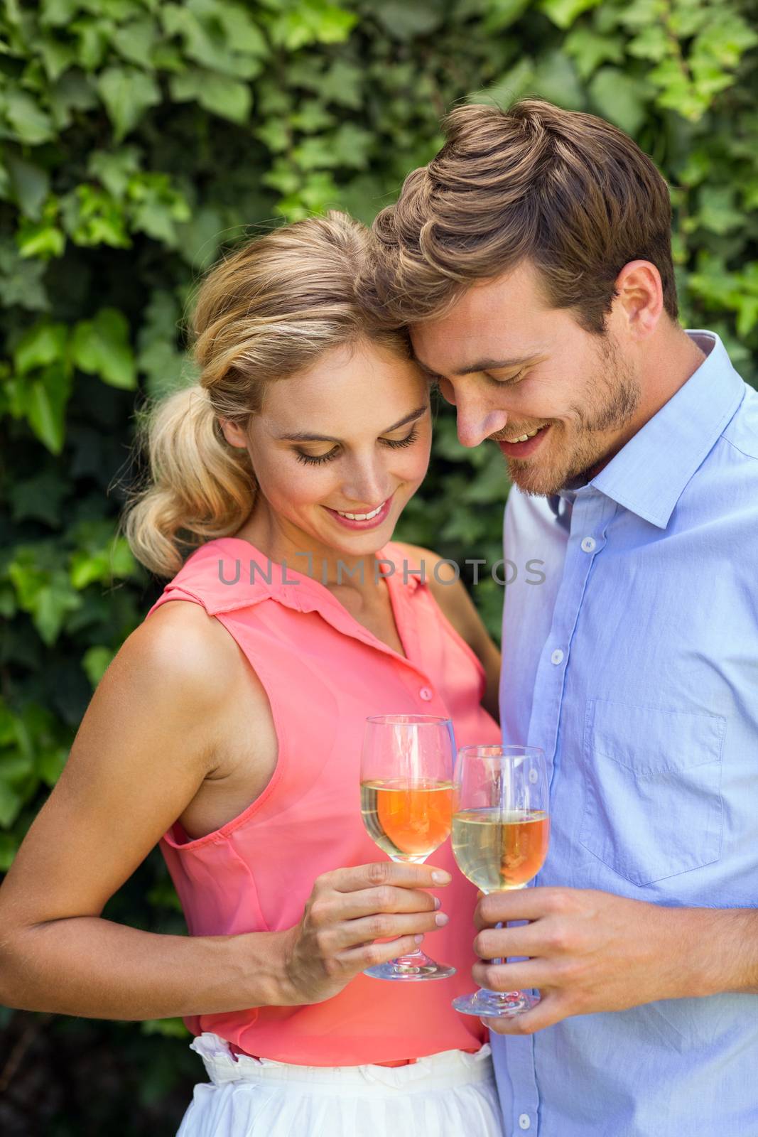 Happy romantic couple toasting wineglasses at front yard