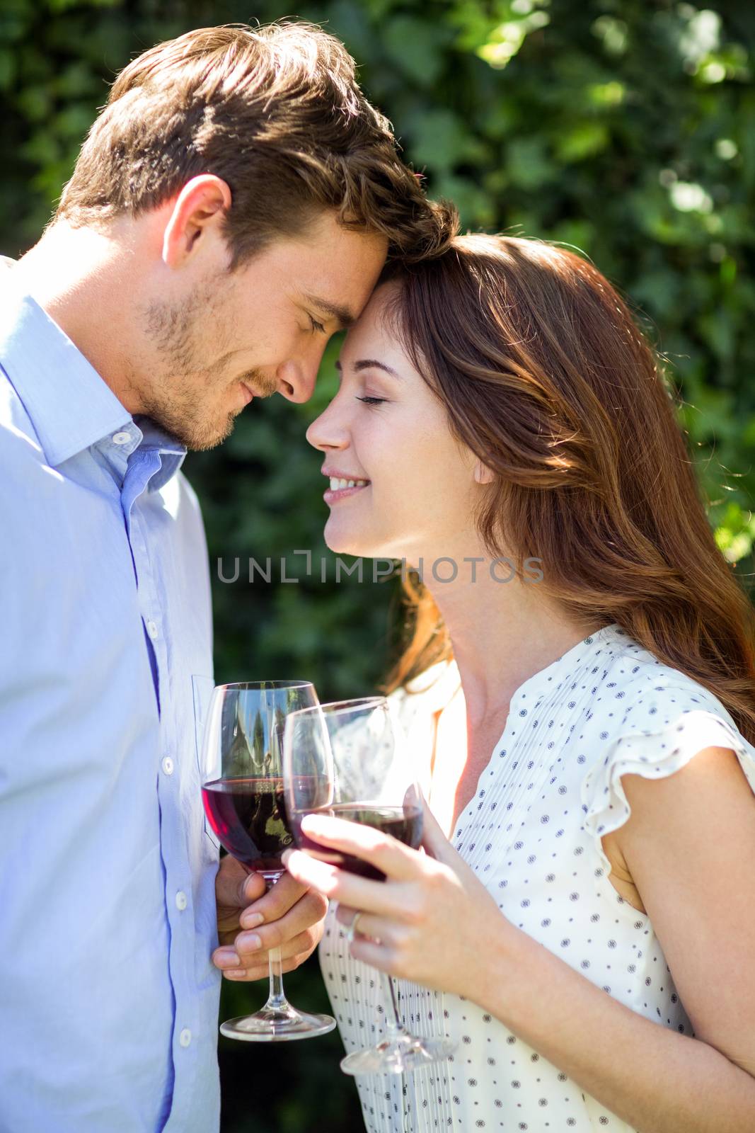 Romantic couple holding wineglasses at front yard