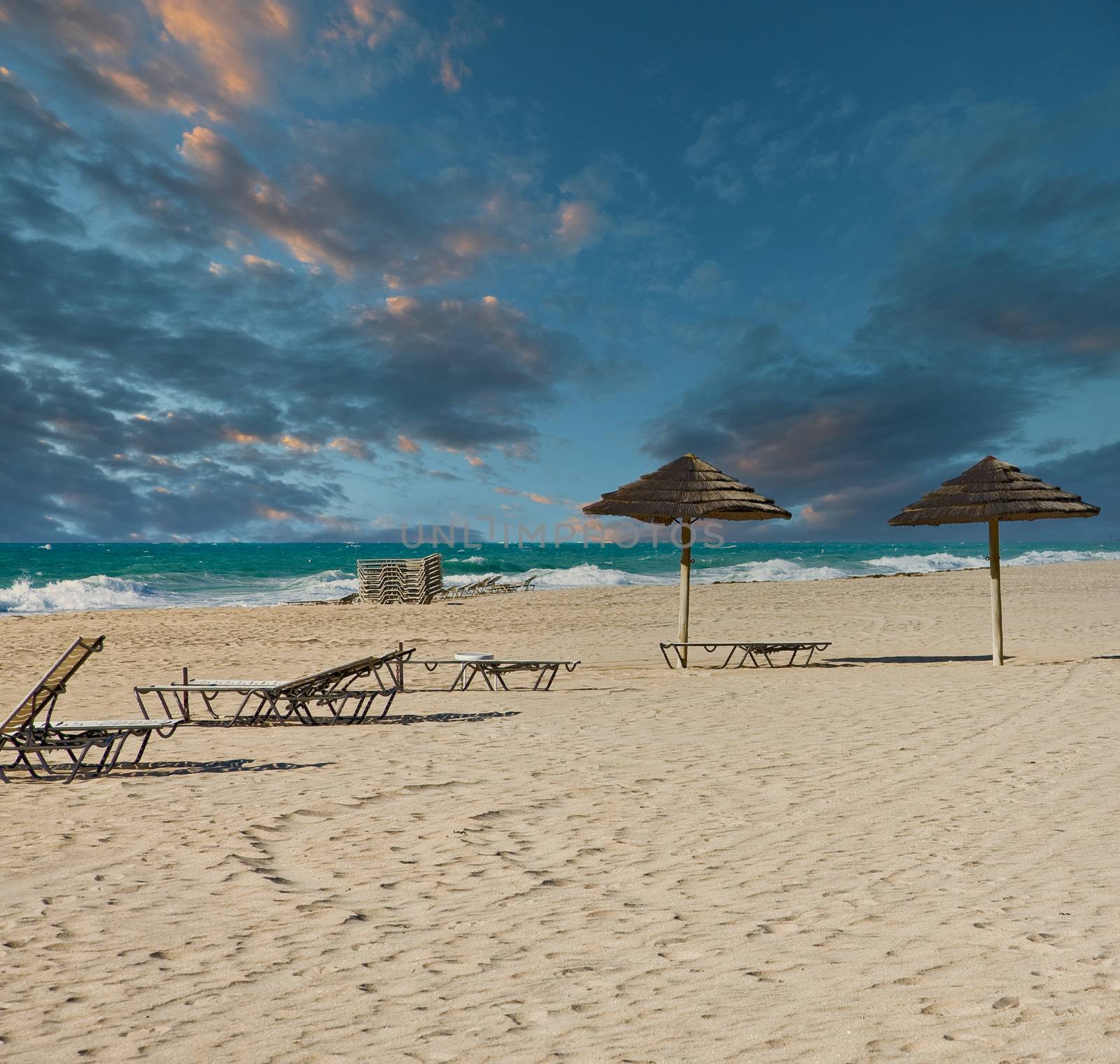 Straw Umbrellas on Beach at Dusk by dbvirago