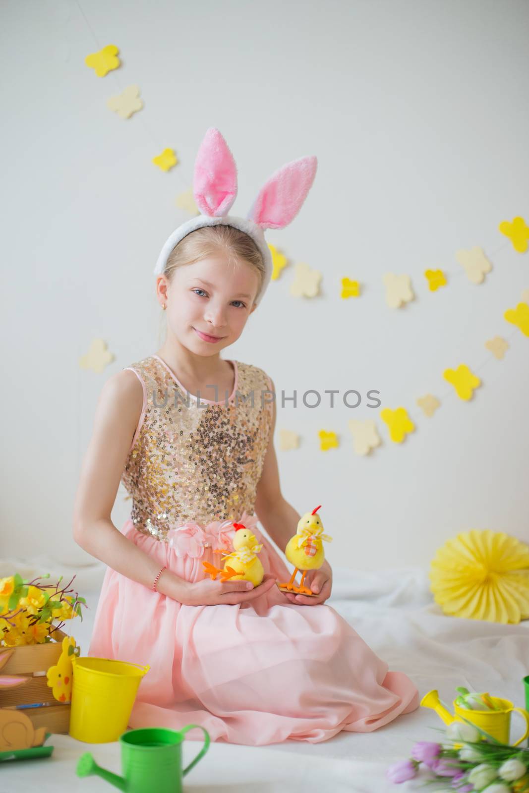 Cute little girl with bunny ears painting eggs, Easter decoration