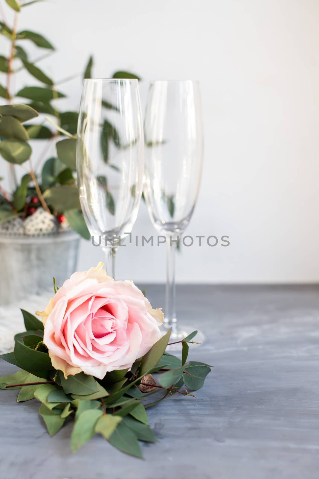 Composition with glass for champagne. Flowers and hearts on grey concrete background