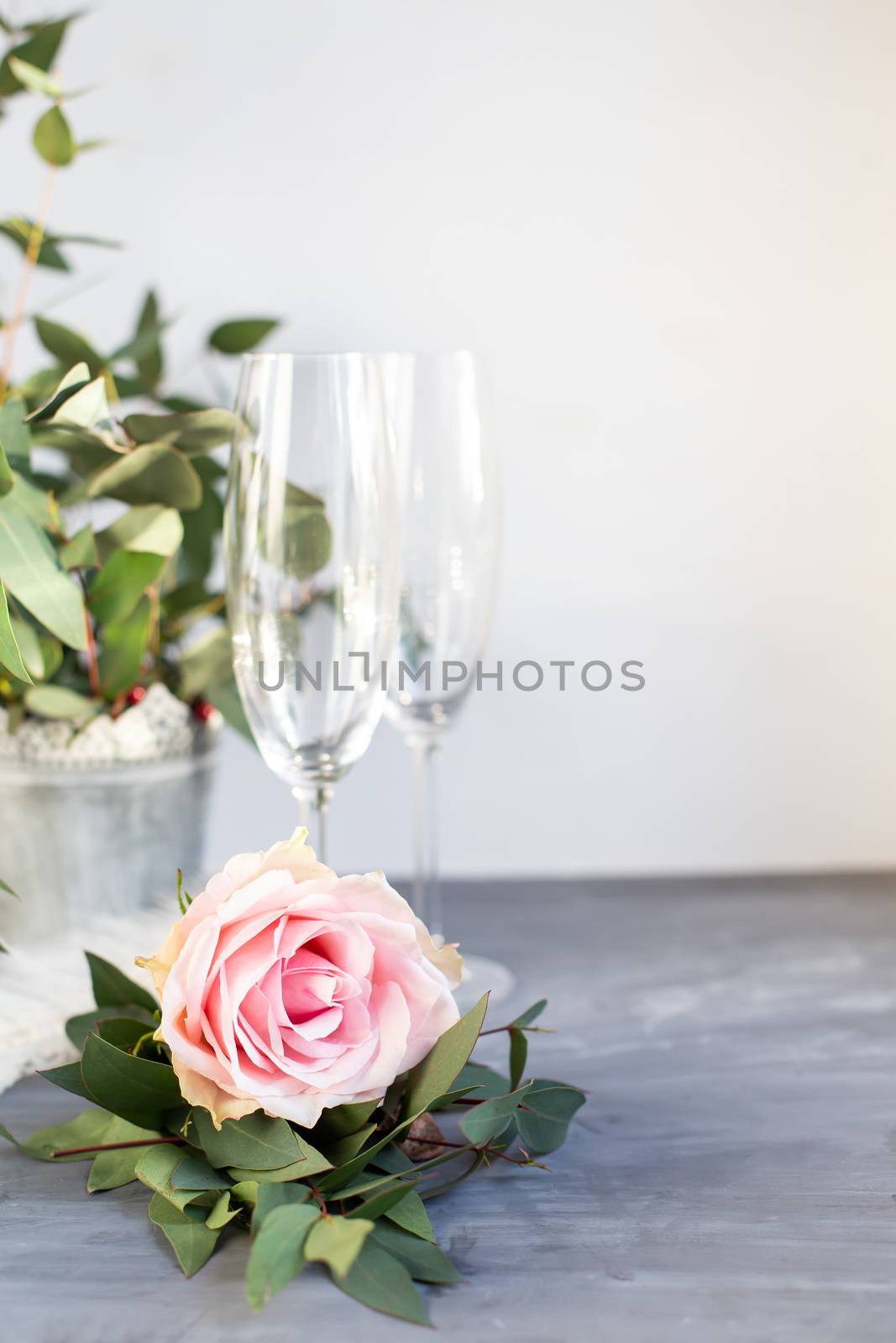 Composition with glass for champagne. Flowers and hearts on grey concrete background